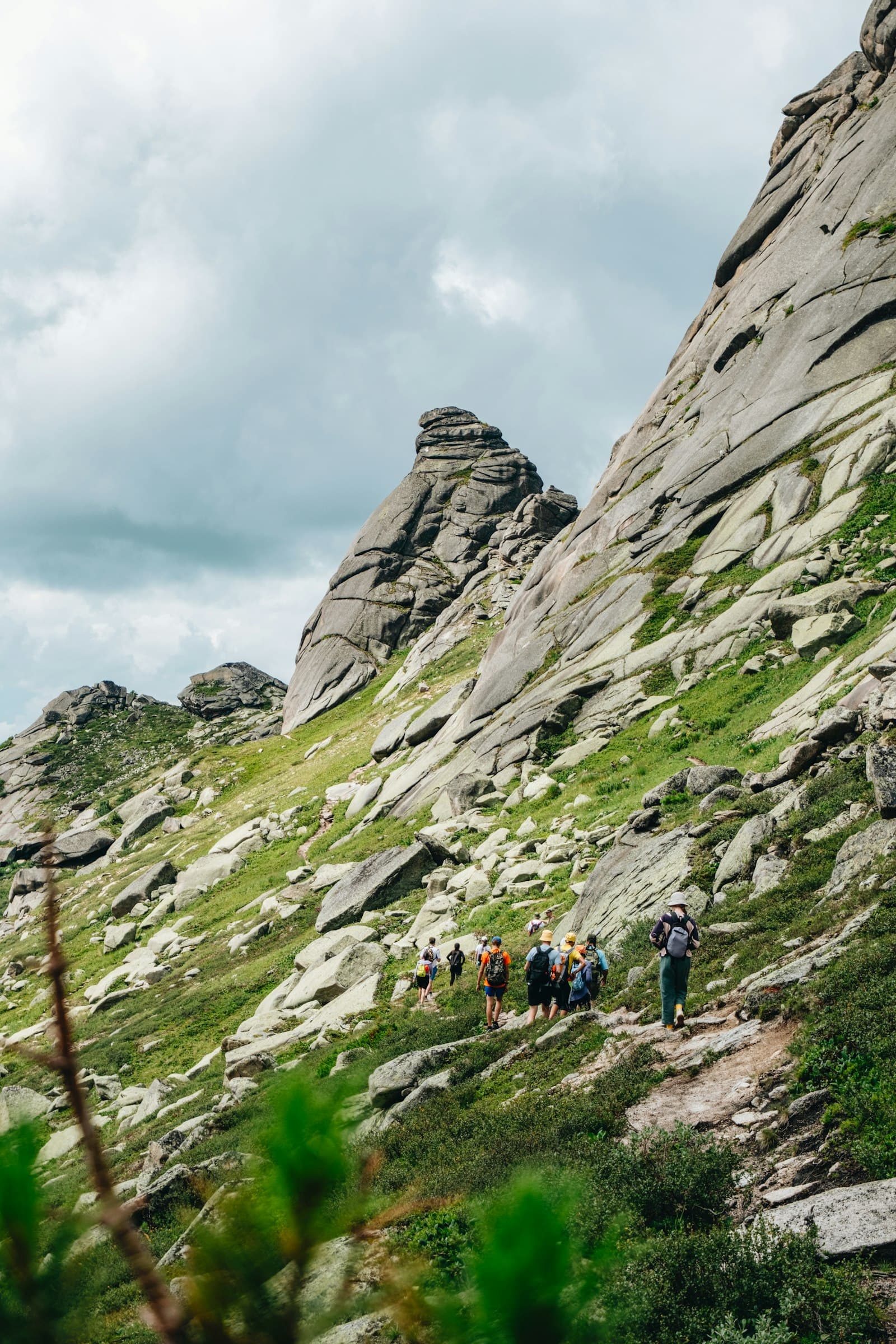 Eine Wandergruppe auf einem Pfad an einem felsigen Berghang