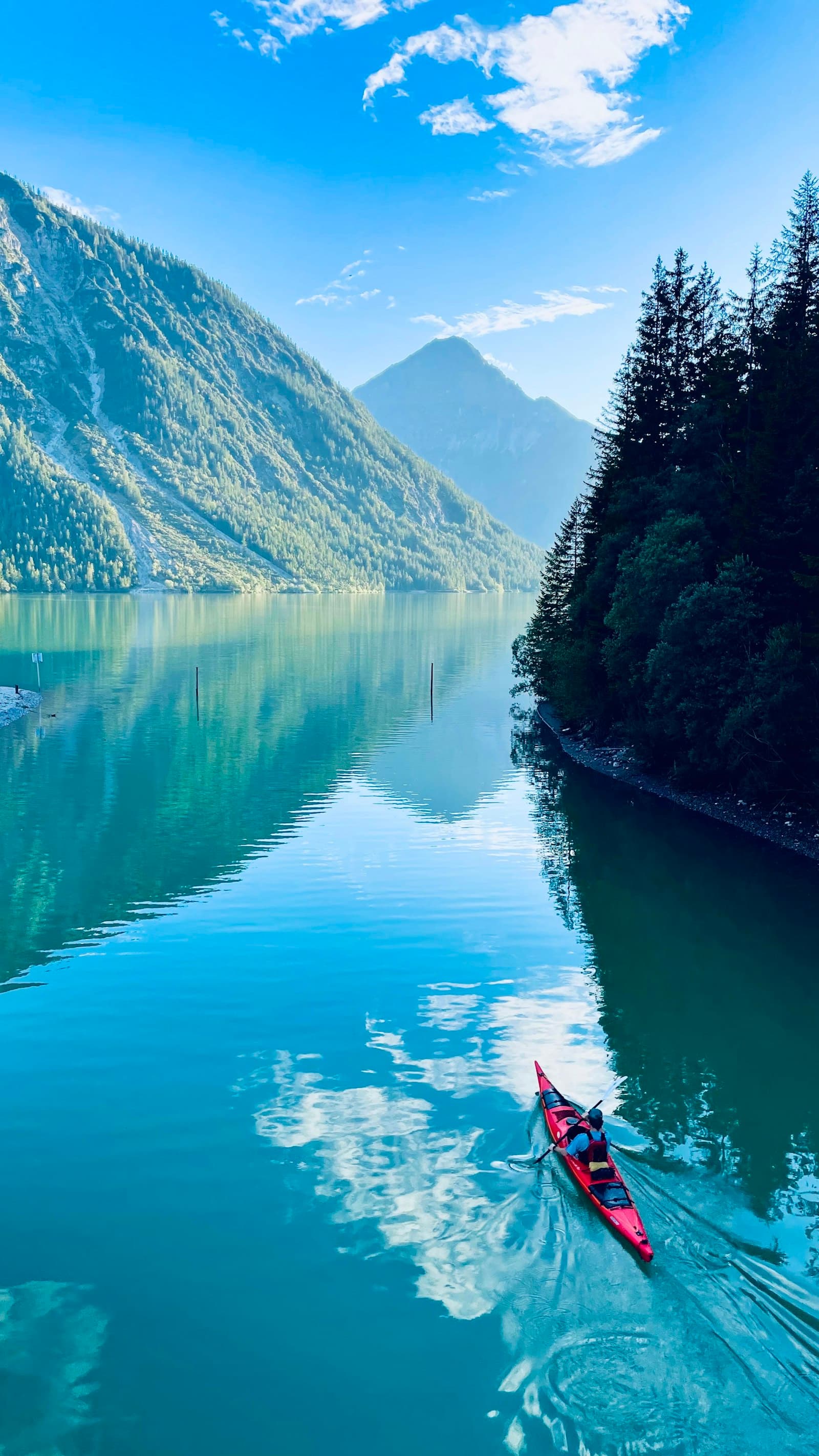 Ein Kajak gleitet über einen ruhigen Alpensee
